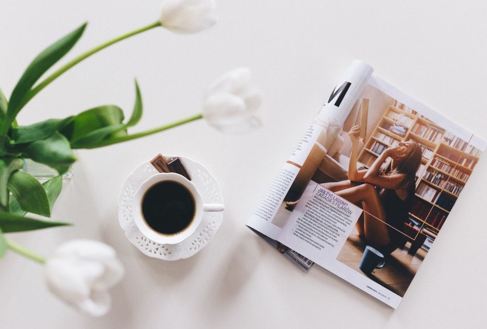 article and online magazine writing services. magazine with a cup of coffee on a white table.
